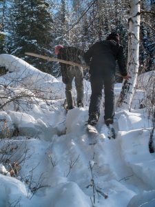 Two skiers climbing through mixed terrain